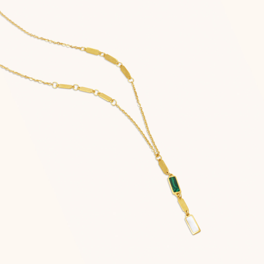 Close-up detail of 18K gold necklace showcasing malachite stone, mother-of-pearl accent, and polished gold links.