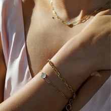 Load image into Gallery viewer, 18K gold chain bracelet with round mother-of-pearl charm worn on a woman's wrist