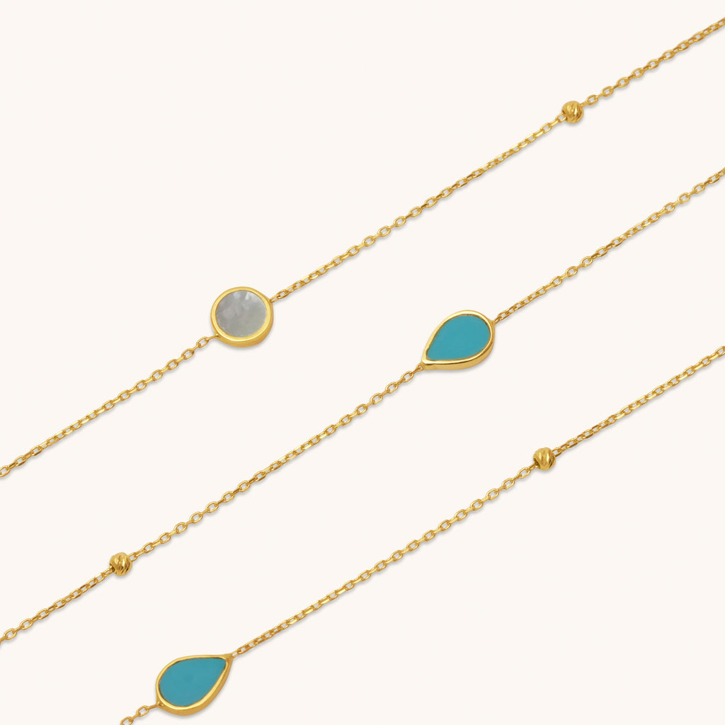 Close-up detail of turquoise stone and mother of pearl elements set on an 18K gold necklace