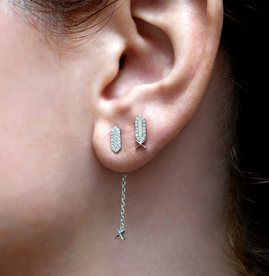 Close-up of an ear wearing two silver diamond stud earringswith a star charm
