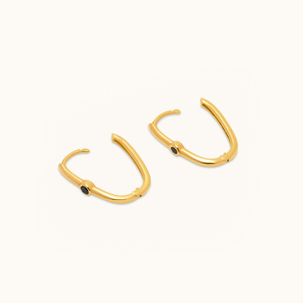 Angled open view of 18K gold hoop earrings highlighting the black diamond setting and smooth hinged design