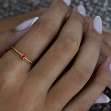 Load image into Gallery viewer, A women wearing a sleek 18k gold ring with a polished band, accented by a central strip of coral enamel and intricate engravings.