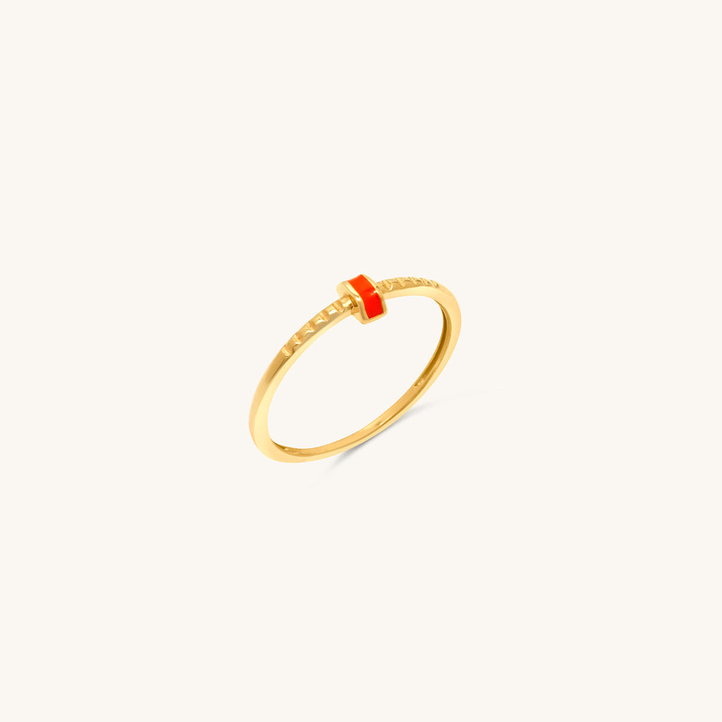 A sleek 18k gold ring with a polished band, accented by a central strip of coral enamel and intricate engravings.