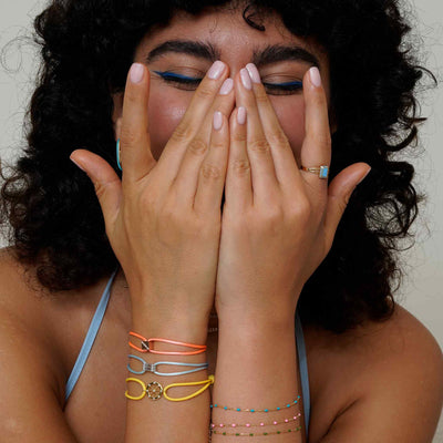a women wearing an 18k gold ring with a blue square enamel inlay set within a metal frame on a white background.