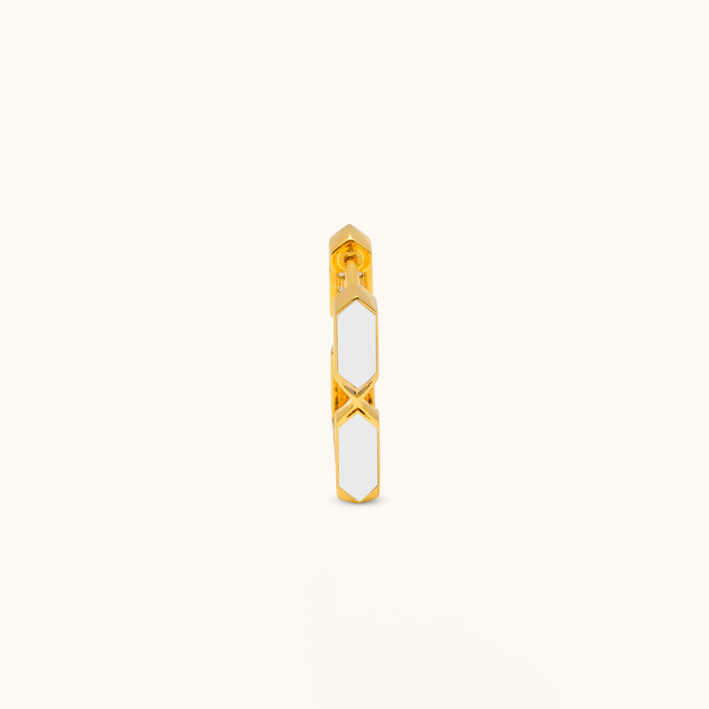 Gold and white enamel hoop earring on a light beige background