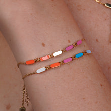 Load image into Gallery viewer, Joubijoux Facets Fusion gold bracelet worn on the wrist with vibrant orange and pink enamel bar detailing