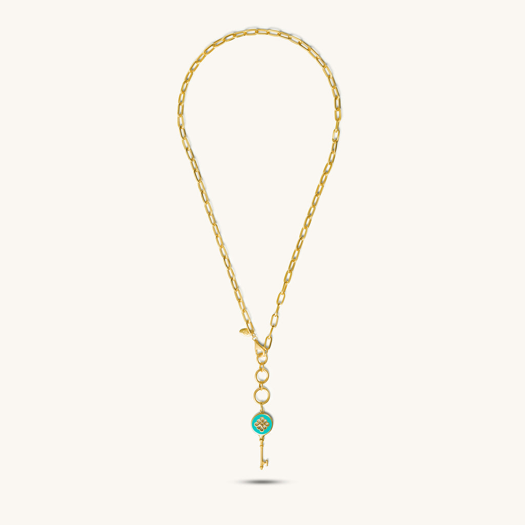 A 18k gold necklace with a golden key pendant featuring a blue enamel center with a floral motif full length