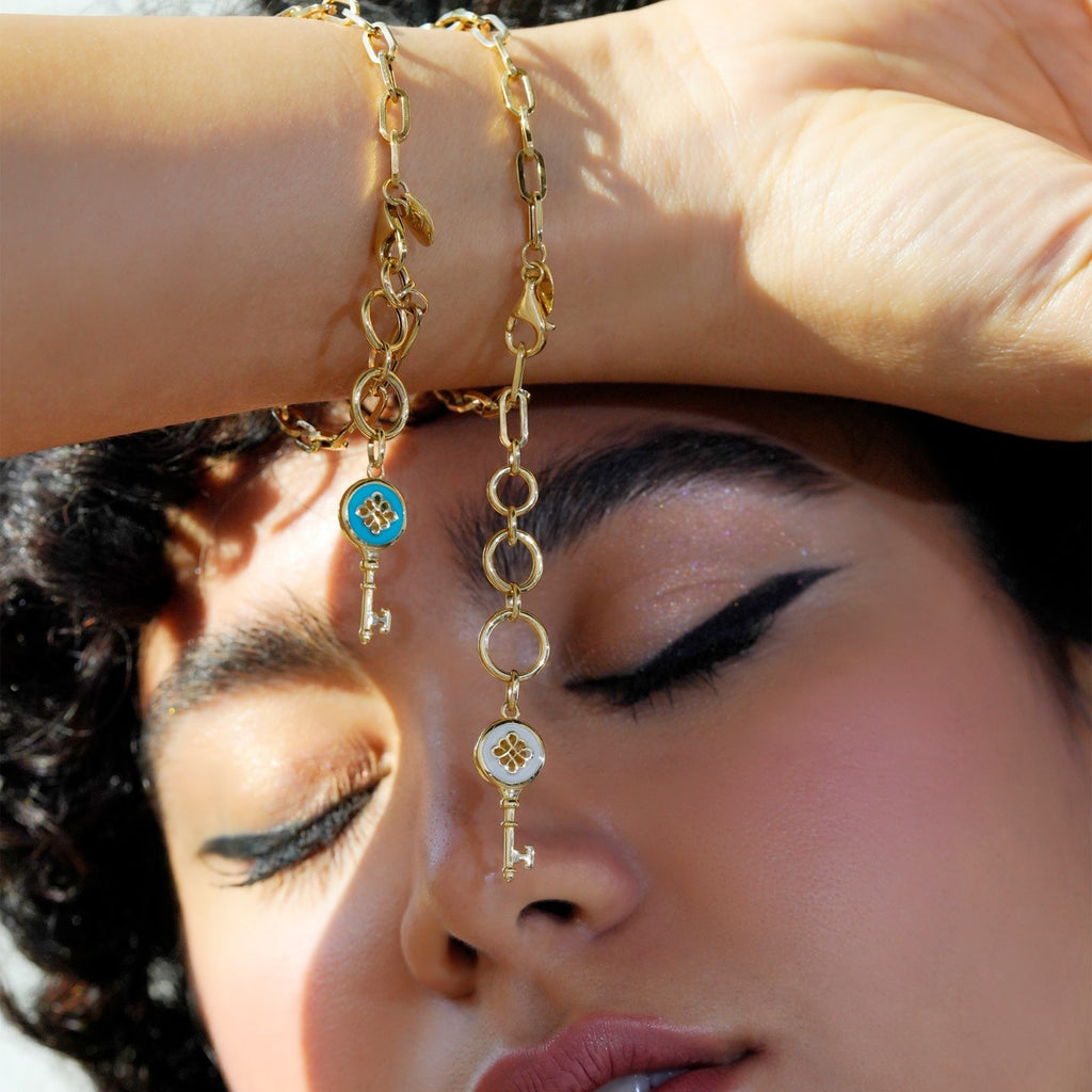 Woman wearing 18K yellow gold bracelet with blue enamel key pendant on wrist