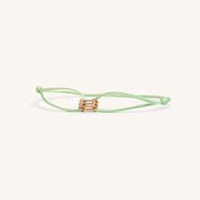 Load image into Gallery viewer, Flat lay of Kaleido Triad rose gold bracelet with pistachio green adjustable thread