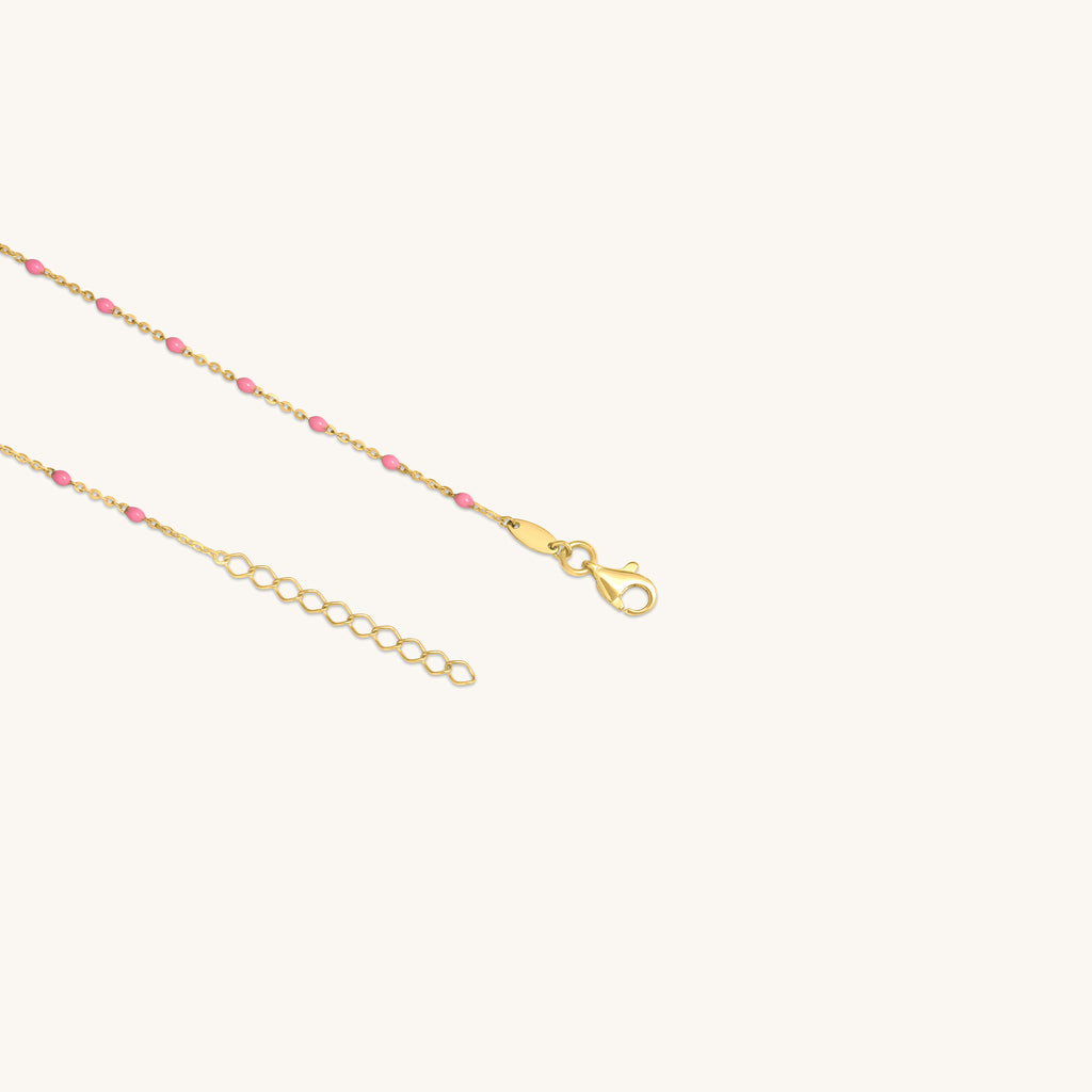 Close-up of pink enamel beads on 18K gold raindrop necklace chain