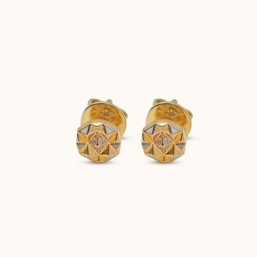Close-up of 18K gold diamond stud earrings with white enamel and faceted slopes motif